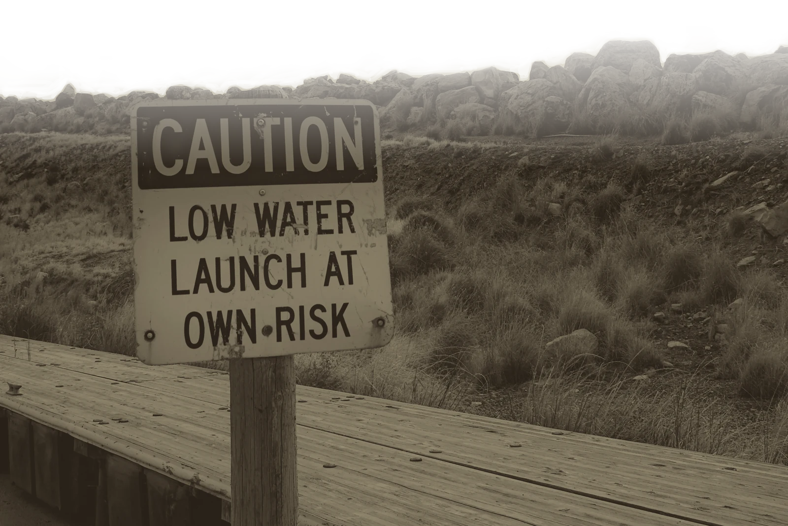 A CAUTION: LOW WATER, LAUNCH AT OWN RISK sign on a wooden launch dock